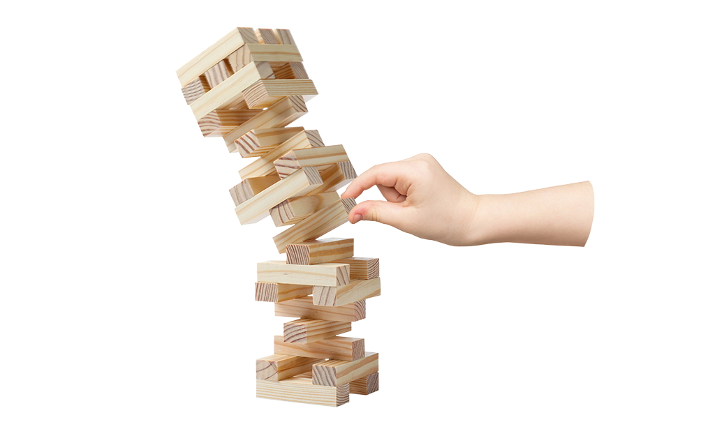 A Jenga tower that's tipping over as a hand pulls a piece out.