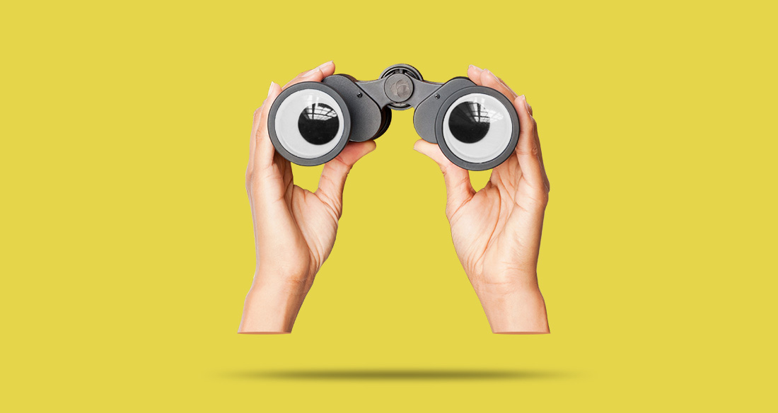 A pair of hands holding binoculars with eyes on the lenses.