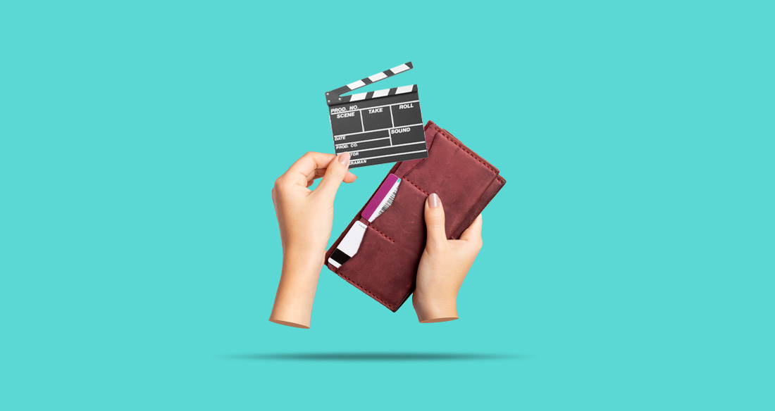 A pair of hands pulling a clapperboard out of a wallet.